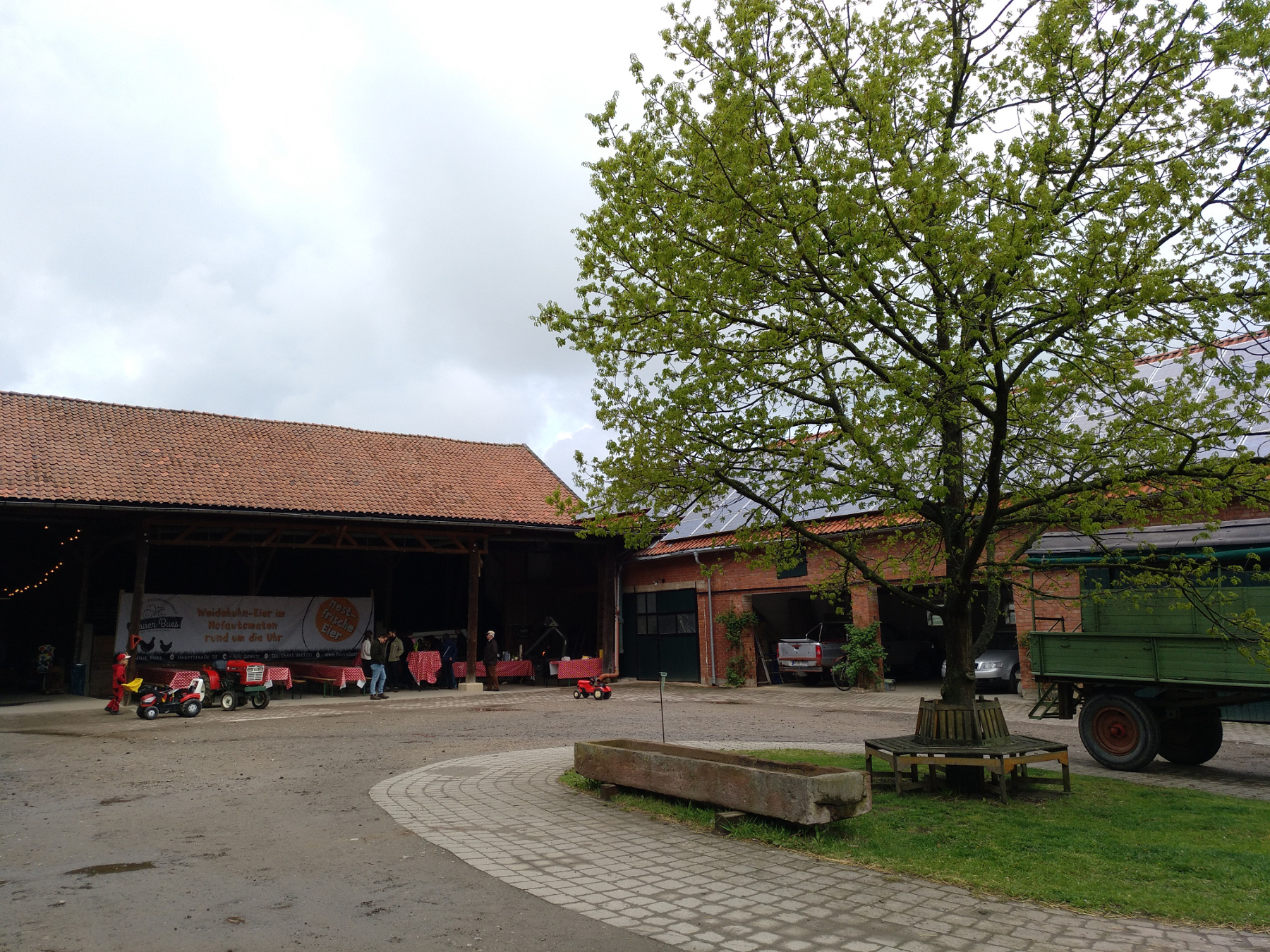 im Innenhof der Hofanlage, mit Baum und Sitzgruppe, dahinter Scheunen